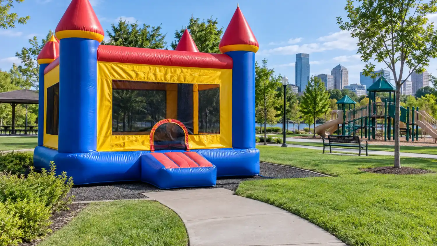 château gonflable commercial installé dans un parc municipal public avec une allée pavée accessible menant à l'entrée